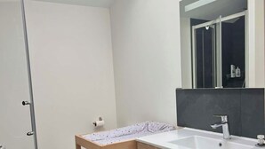 Une salle de bain moderne avec une douche à parois de verre, un meuble-lavabo en bois et un miroir au-dessus du meuble.