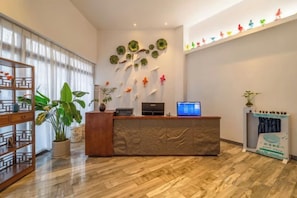 Een receptie met een houten receptiebalie, een computerscherm en een potplant.