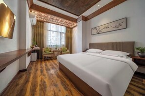 A hotel room with a large bed, wooden flooring, a desk, and a chair. - Taoshe Art Hotel (Jingdezhen People's Square) (Jingdezhen)