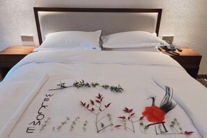 Een net opgemaakt bed met een bloemenmotief en de tekst 'WELCOME' op de spreidekker.
