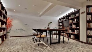 A room with a dining table, chairs, bookshelves, and a decorative wall mural.