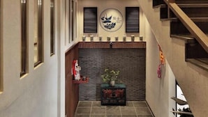 A modern interior with a staircase, a decorative wall with a circular emblem, and a small table with a plant.