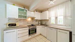 A modern kitchen with white cabinets, a built-in microwave, a stove, and a dishwasher. - Seafront Villa Goga by Villas Guide (Vela Luka)