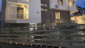 A modern multi-story building with balconies, air conditioning units, and a well-lit entrance. - SGI APARTMENT (Abuja)