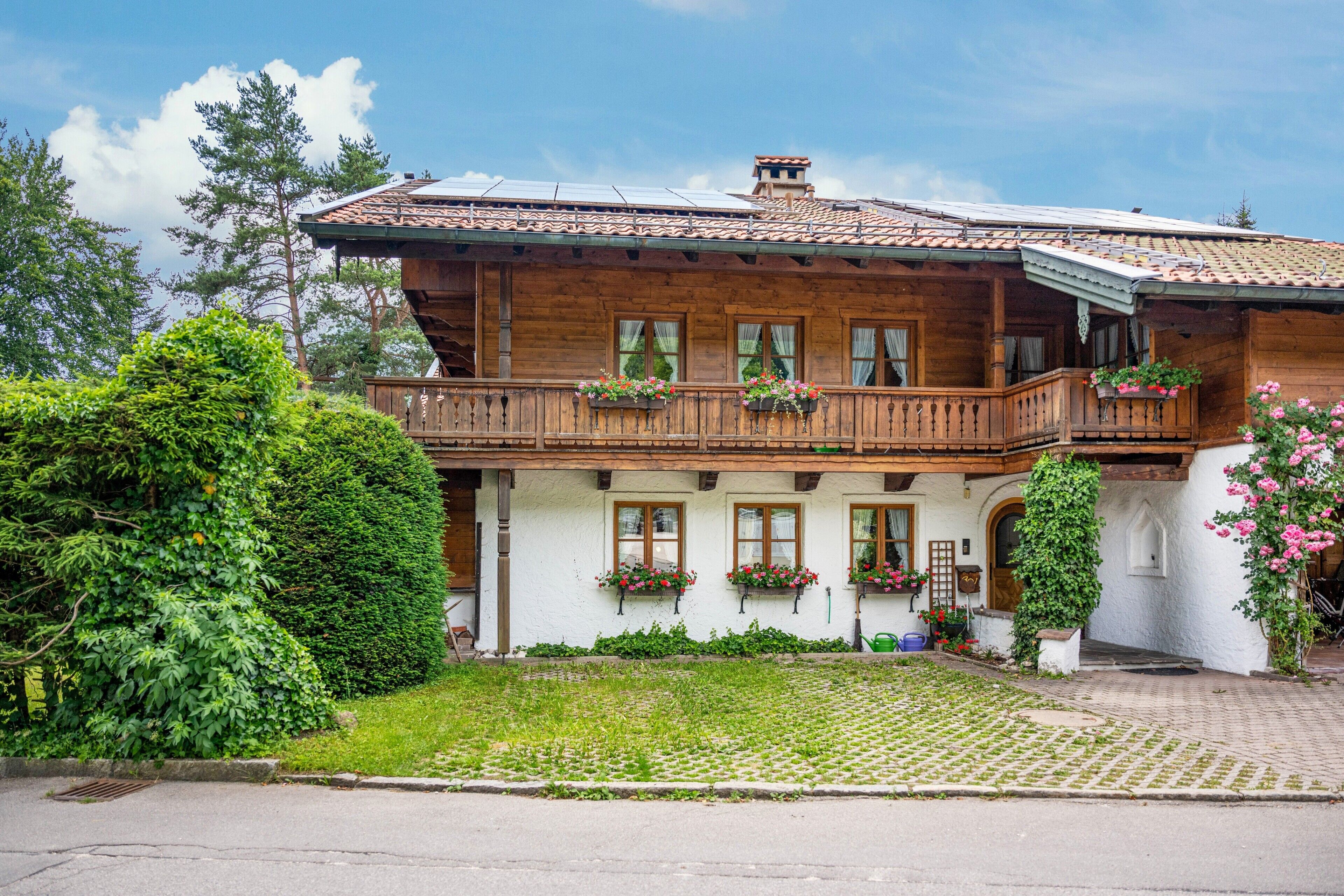 Ein Holzhaus mit Balkon, Fenstern und einem Garten.