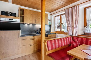 Una cucina con mobili in legno, forno a incasso e zona pranzo con una panca e un tavolo.