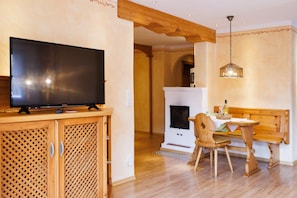 A room with a television on a wooden cabinet, a fireplace, a wooden bench, and a hanging light fixture.