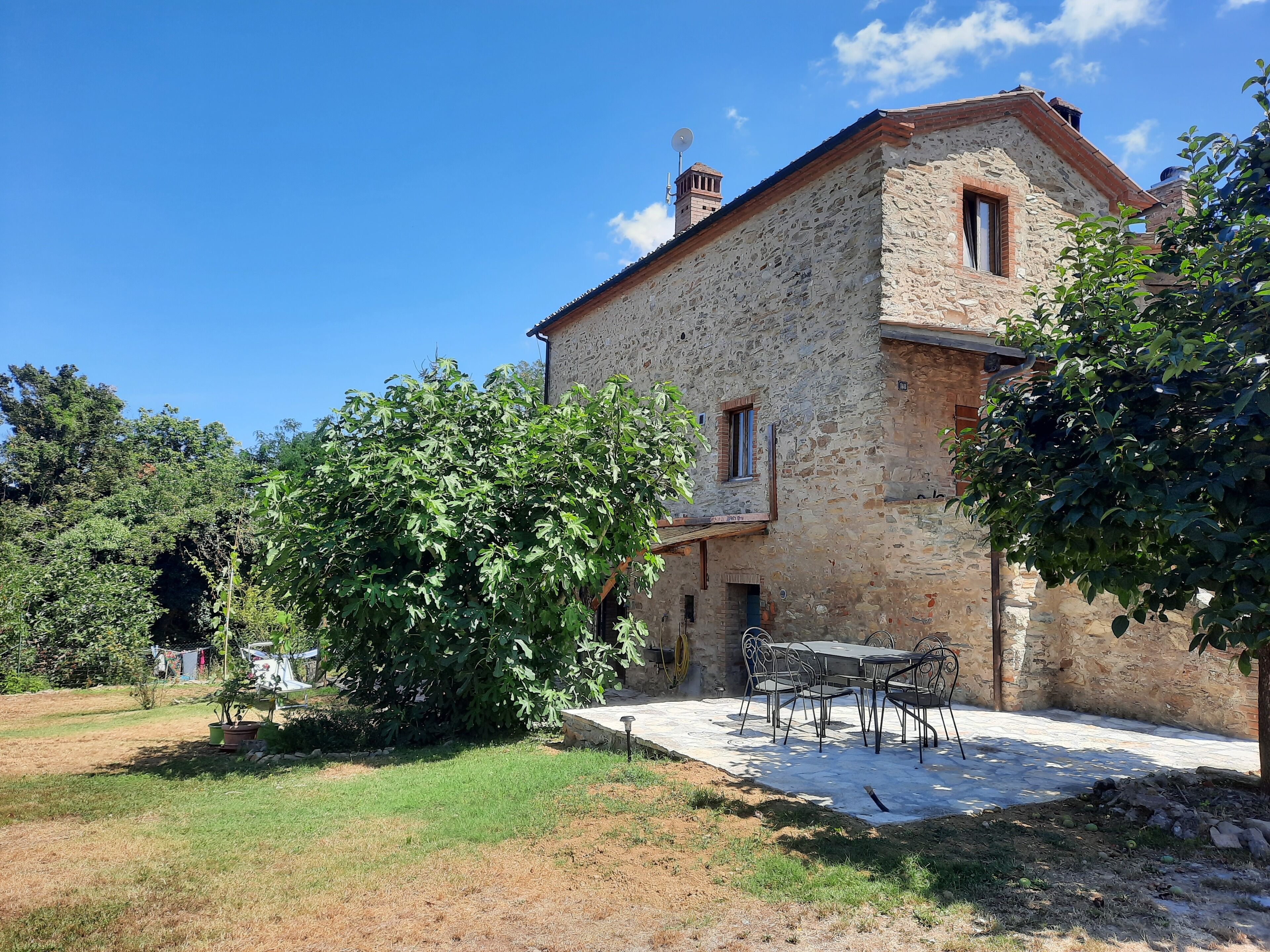Un bâtiment en pierre doté d’une terrasse et de sièges extérieurs.