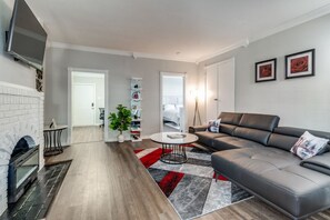 A modern living room with a fireplace, a sectional sofa, a round coffee table, and a red and gray rug. - Executive 1BR in Oak Lawn, Courtyard, Work Space, Gated Community (Dallas)