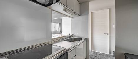A modern kitchen with a built-in stove, two sinks, and white cabinetry.