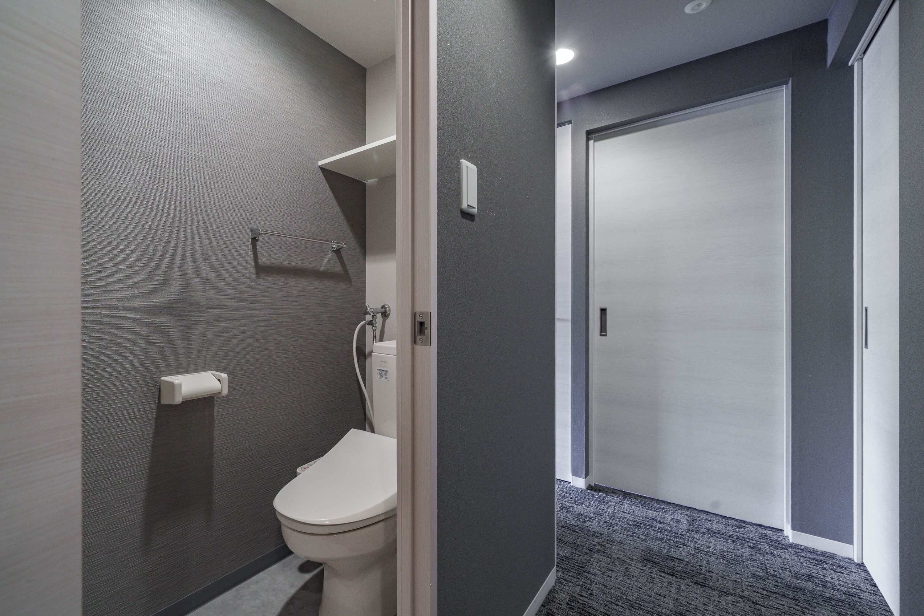 Un baño moderno con inodoro, toallero y zona de ducha.