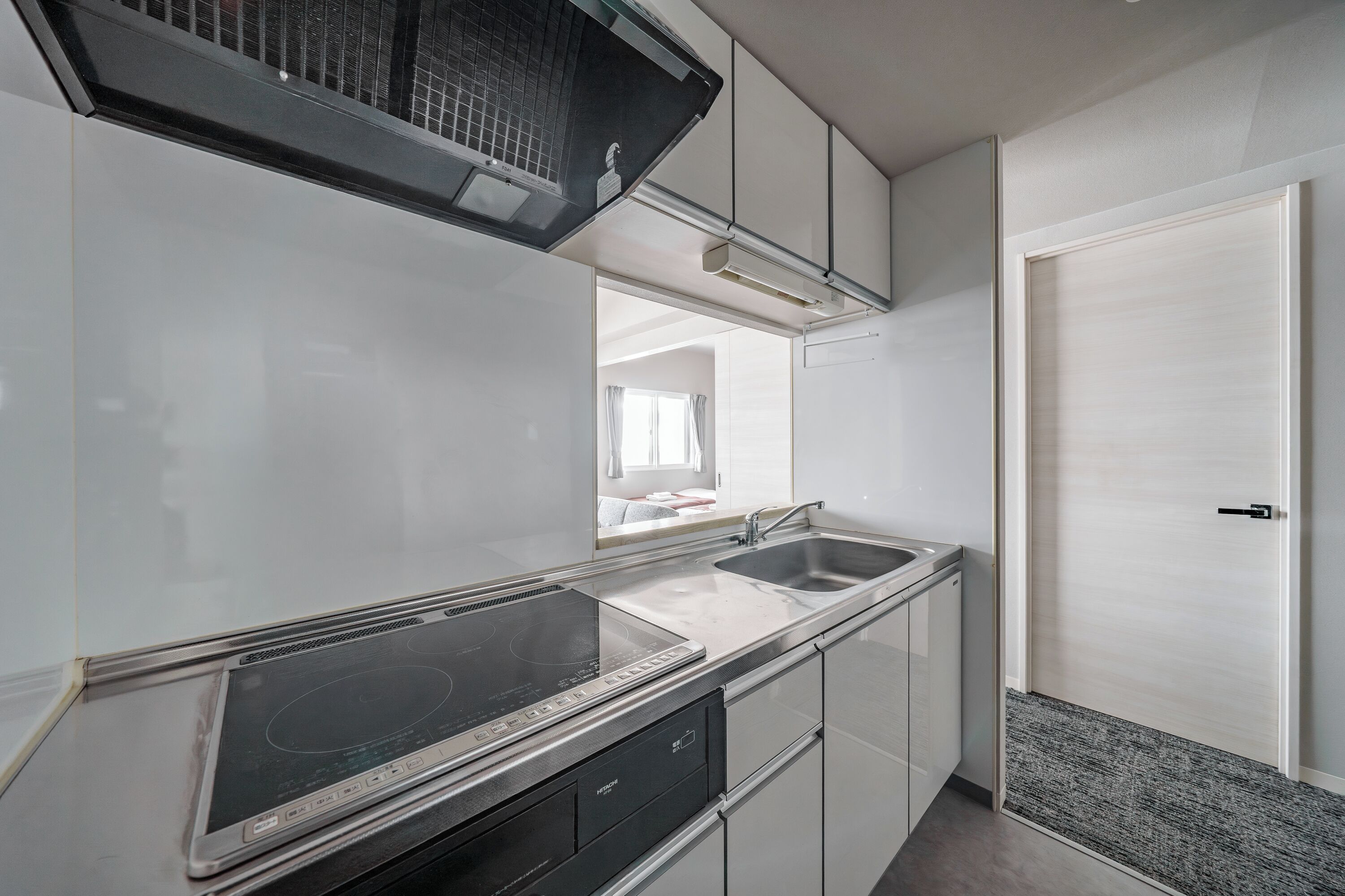 Een moderne keuken met een ingebouwd fornuis, een dubbele spoelbak en witte kasten.