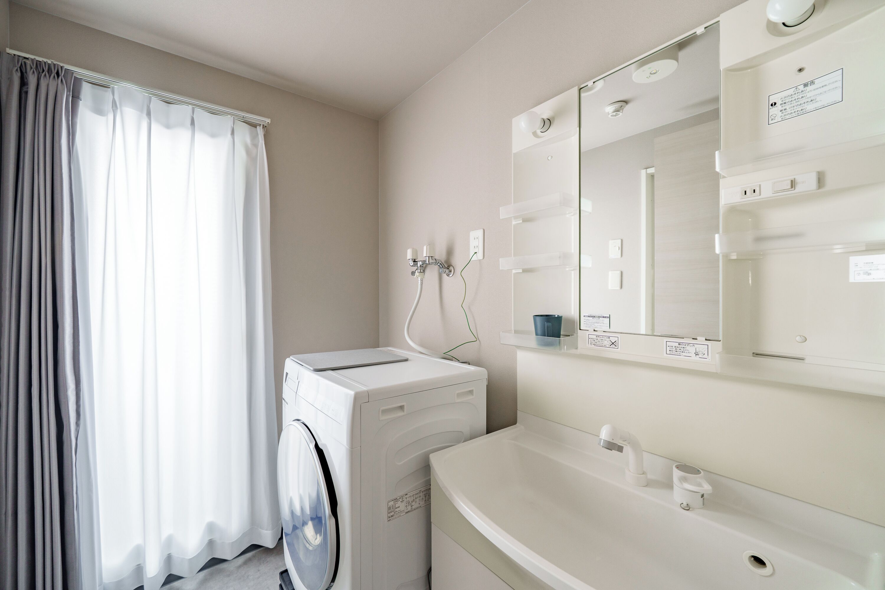 A modern bathroom with a washing machine, a sink, and a mirror.
