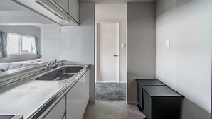 A compact kitchen with a large sink, cabinets, and a door leading to another room. - MP STYLE SAPPORO-50 (Sapporo)