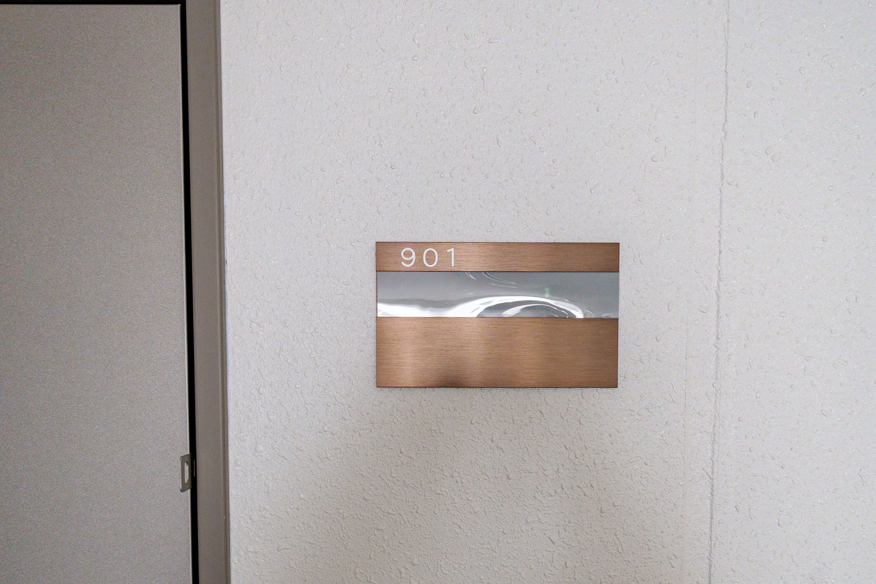 Eine an der Wand befestigte Schilder mit der Nummer 901, die ein Zimmer oder Büro kennzeichnet.