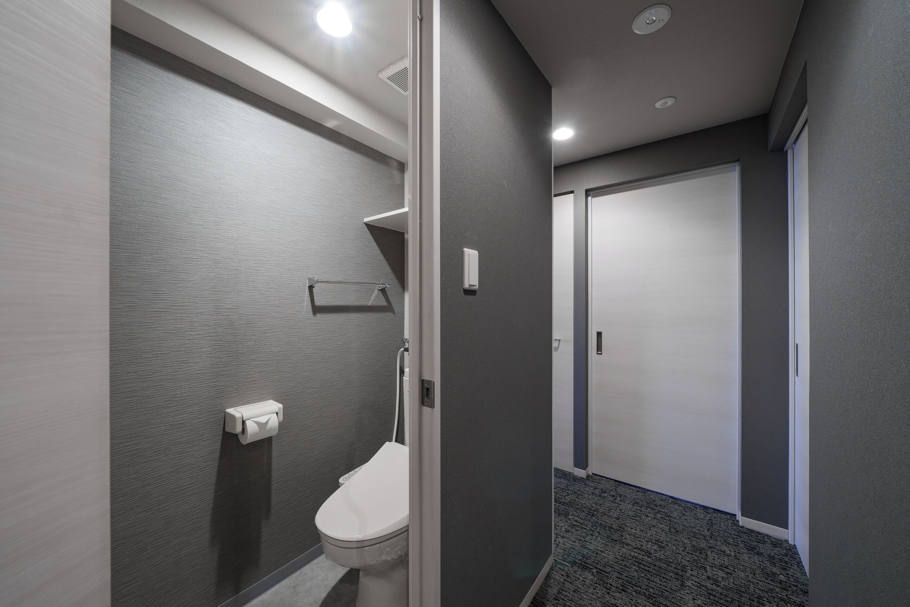 Et moderne badeværelse med toilet, håndklædedispenser og bruseområde.
