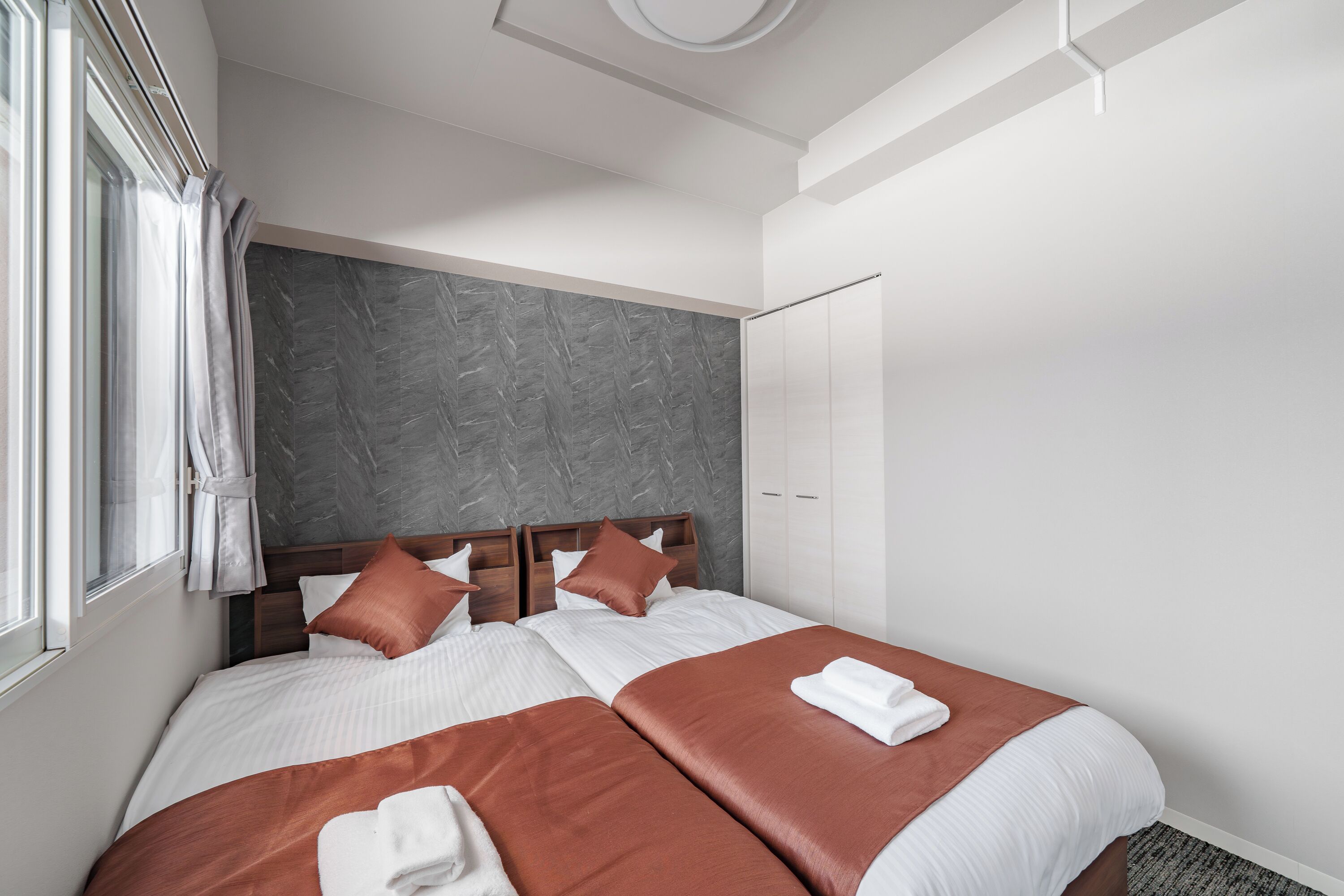 Een moderne hotelkamer met een groot bed, een kledingkast en een raam met gordijnen.