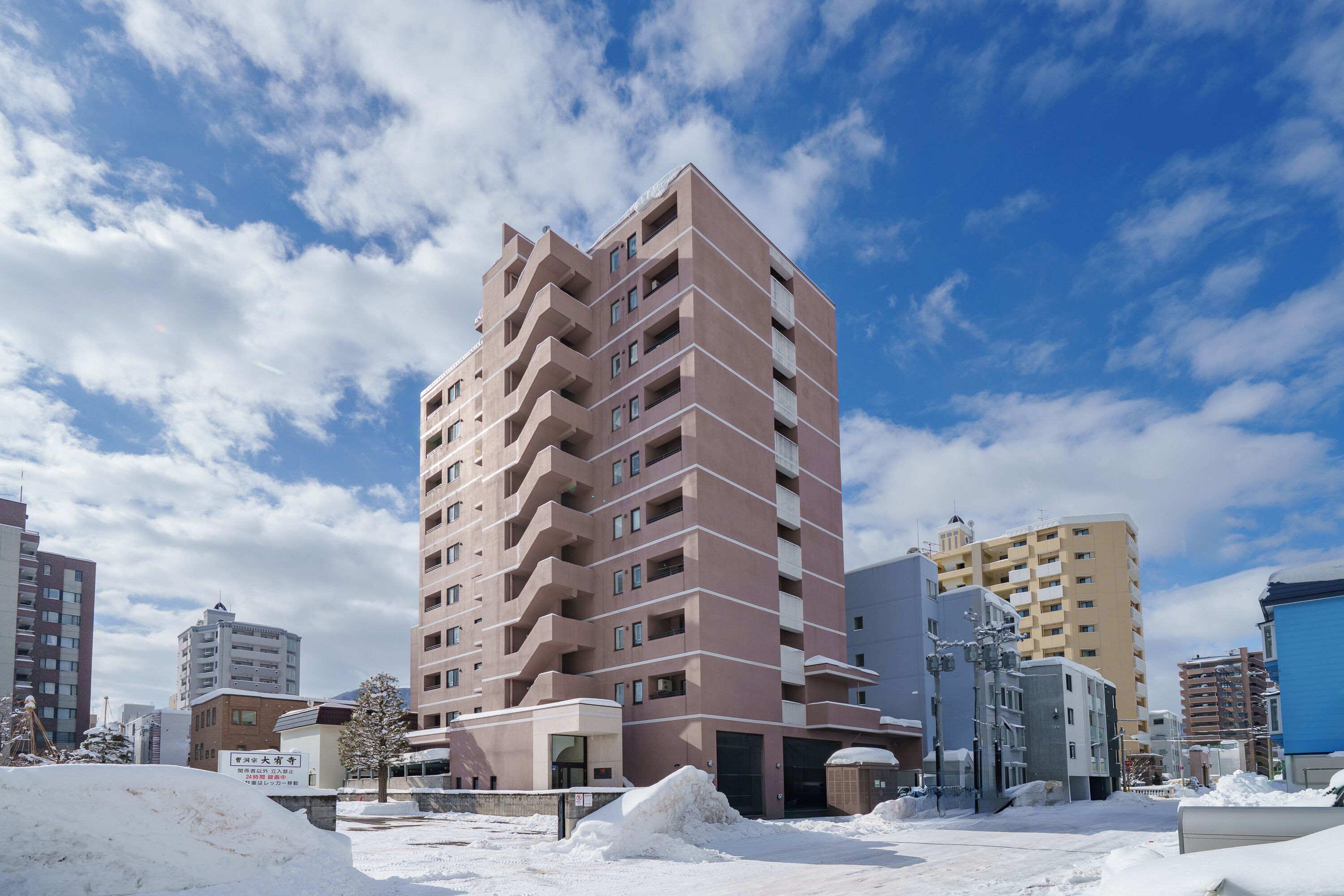 A multi-story building with a modern architectural design, featuring a prominent central staircase and multiple balconies.