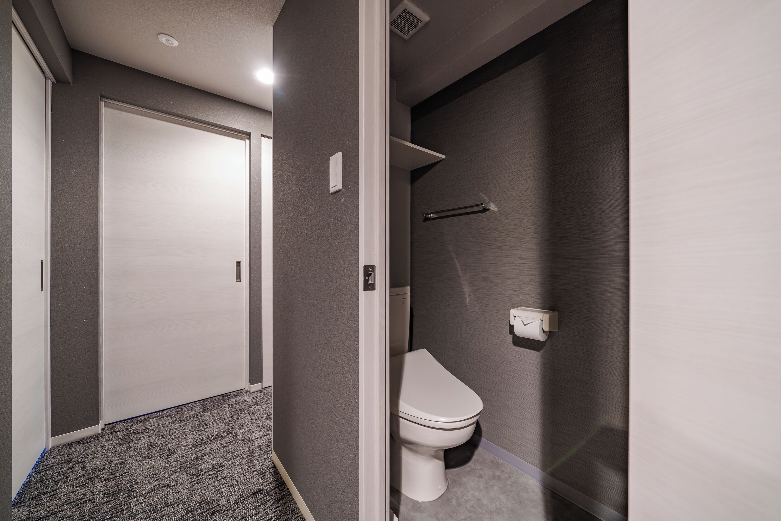 Un baño moderno con inodoro, toallero y zona de ducha.