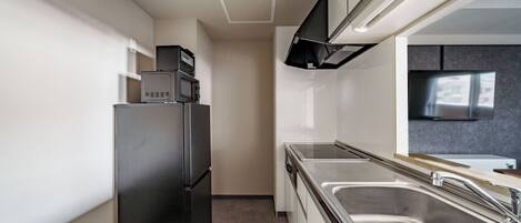 Una cocina moderna con un refrigerador de acero inoxidable, horno empotrado, microondas y un lavamanos grande.