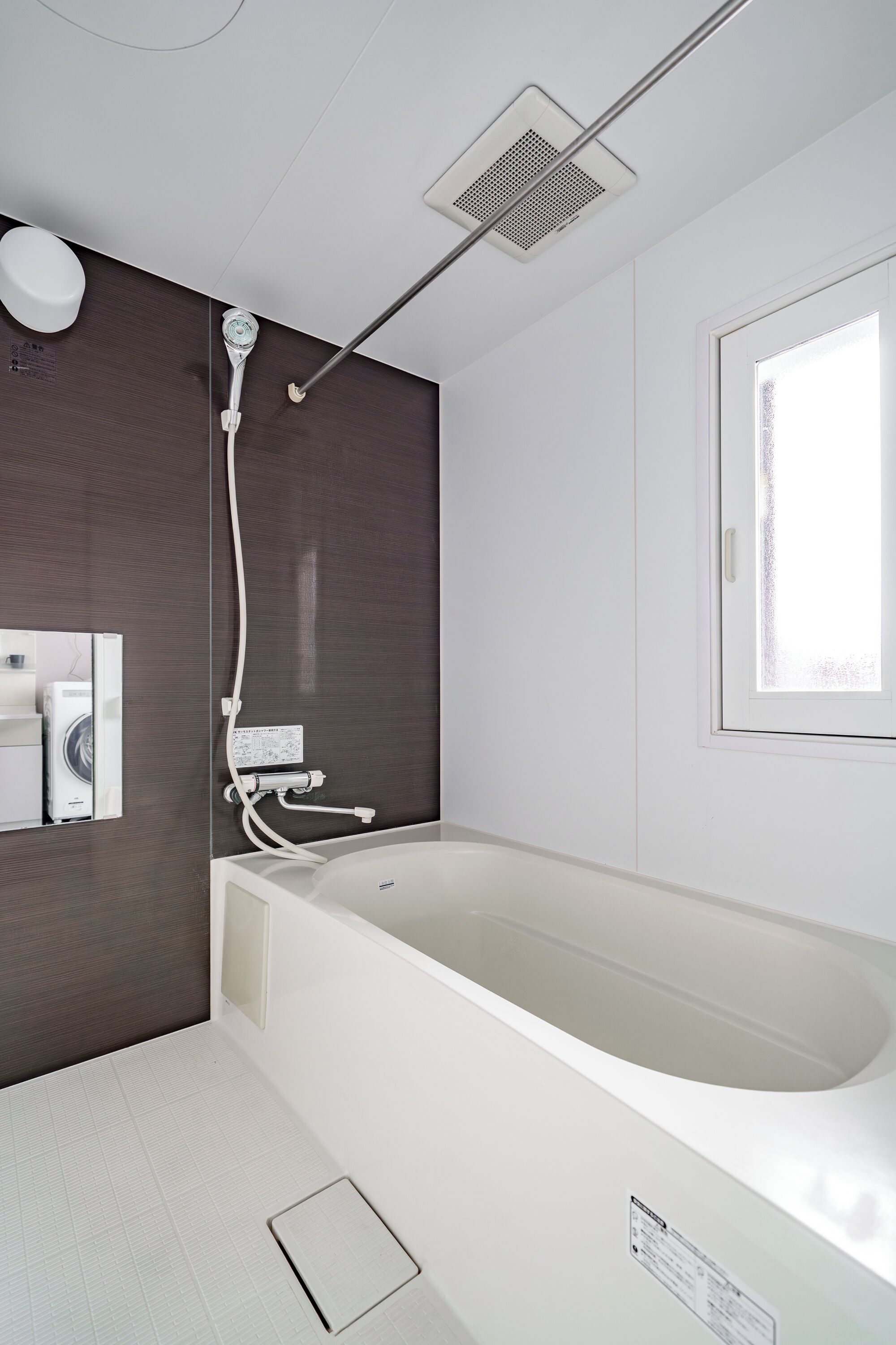 A modern bathroom with a large bathtub, a showerhead, and a window.