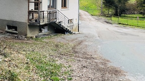A two-story house with a tiled roof, a small balcony, and a staircase leading to the entrance. - Apartment in the heart of the Dessoubre valley (Battenans-Varin)