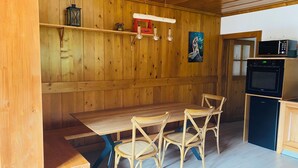 A wooden interior with a dining table, four chairs, a microwave, and a small refrigerator. - Apartment in the heart of the Dessoubre valley (Battenans-Varin)