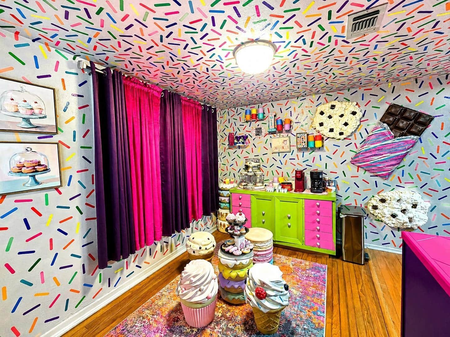 A room with colorful decor, a pink curtain, a green cabinet, and various food items on the wall.