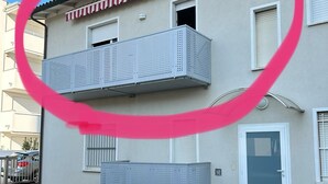 Ein zweistöckiges Gebäude mit einem Balkon im oberen Geschoss und einer Garagentür im Erdgeschoss.
