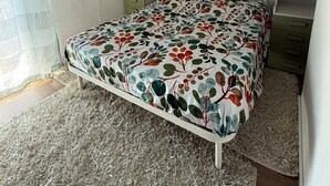 Ein Schlafzimmer mit einem Bett, weißen Schränken, einer Pendelleuchte und einem Spiegel an der Wand.