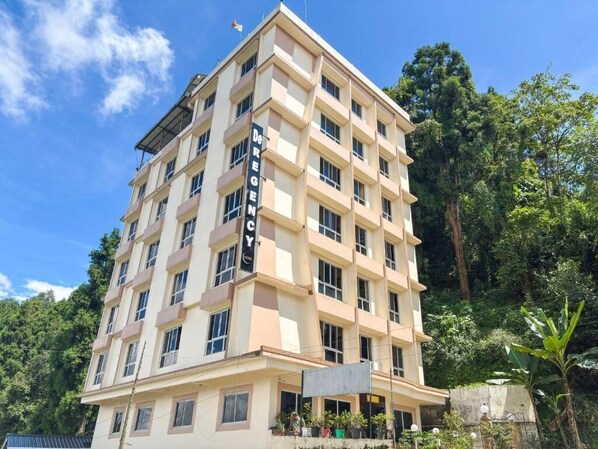 A multi-story hotel with a beige facade, multiple balconies, and a sign indicating it is a hotel. - Rare Himalayas De Regency (Gyalshing)