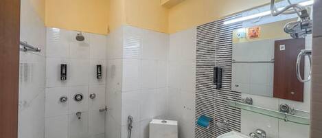 A bathroom with a toilet, shower, sink, and a mirror.