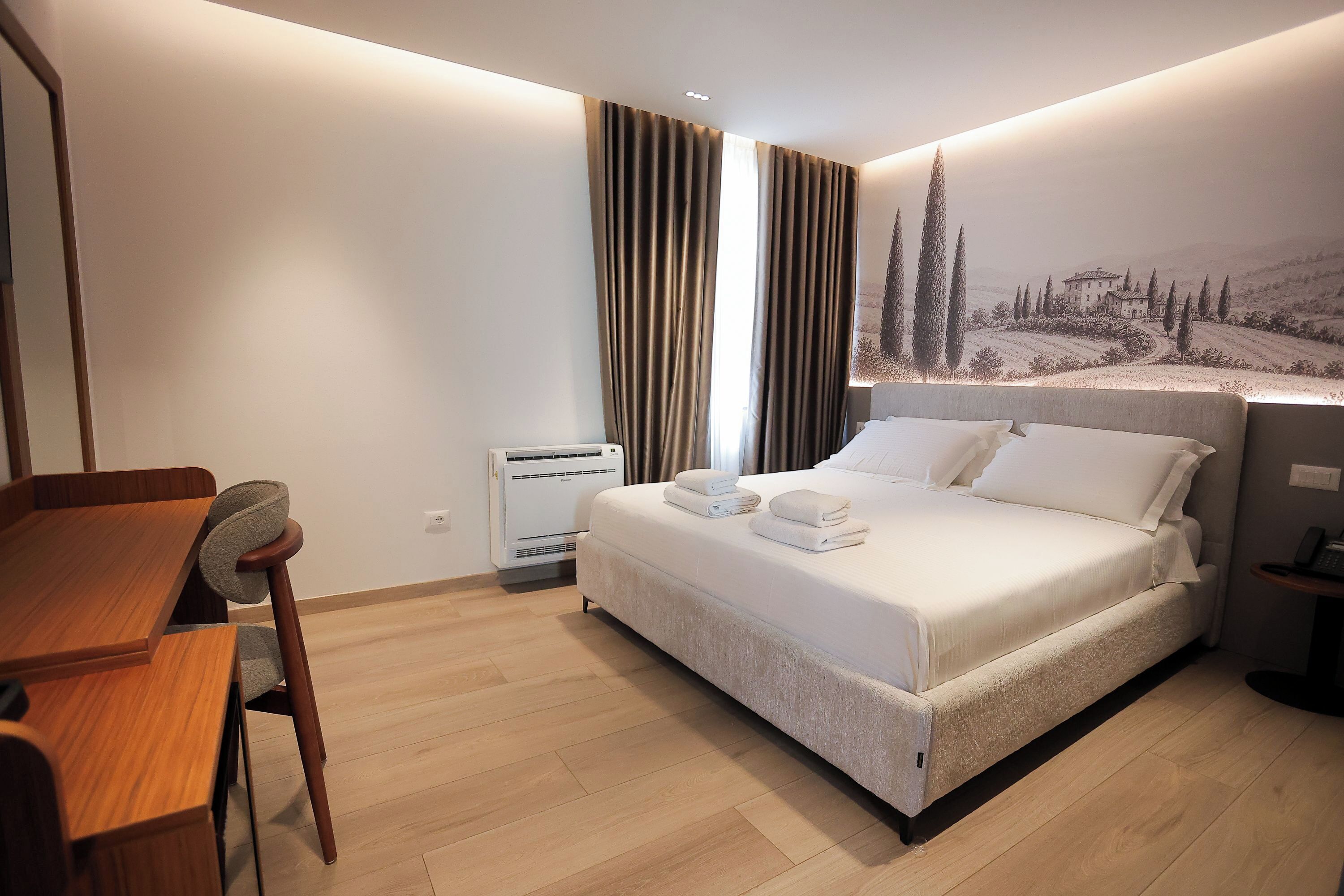 Une chambre d’hôtel équipée d’un lit, d’un bureau, d’une chaise, d’un climatiseur et d’un téléphone fixé au mur.