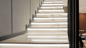 Eine moderne Treppe mit Marmorverkleidung, die zu einem Raum mit Schreibtisch und Computer führt.