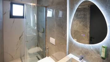 A modern bathroom with a glass shower enclosure, a vanity with a sink, and a large mirror with an arch above it.