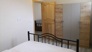 Une chambre à coucher comprenant un lit, une armoire et une porte donnant sur une autre pièce.
