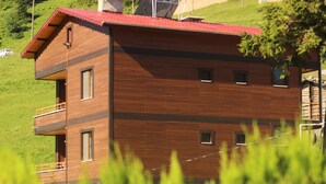 Un immeuble en bois à plusieurs étages, doté de balcons, situé sur une colline.