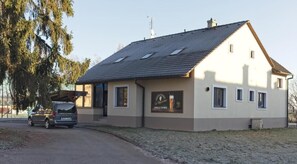 A single-story building with a sloped roof, a small porch, and a parked car. - Penzion U Massima (Vyskov)