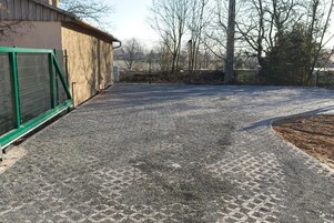 A gravel driveway leading to a building with a green metal gate.