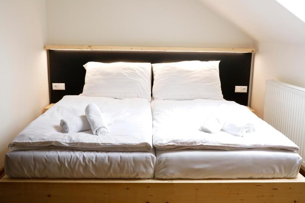 A twin bed with white linens and towels, a wooden headboard, and a sloped ceiling.