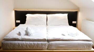 A twin bed with white linens and towels, a wooden headboard, and a sloped ceiling.