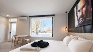 A modern hotel room with a large bed, a dining table, and a view of the outside. - Studio #7 - Steve Jobs | A/C • 5 min downtown (Québec City)
