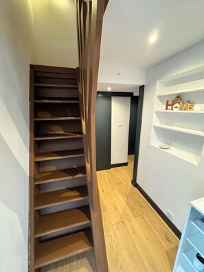 A modern interior with a wooden staircase, a white wall with a 'HOME' sign, and a wooden floor. - CasaLaudi - Sea view apartment (Brando)