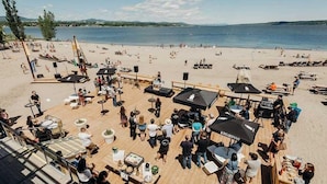 Een restaurant aan het strand met terras, tafels en parasols.