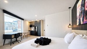 Een moderne hotelkamer met een groot bed, een bureau en een kitchenette.