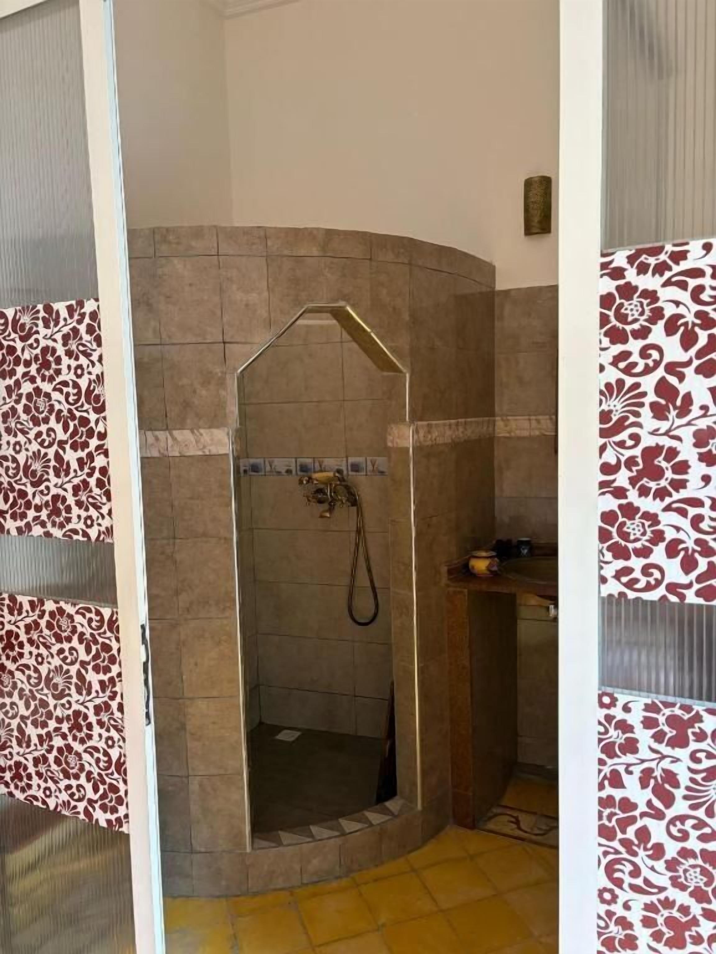 A shower area with a curved design, tiled walls, and a showerhead.