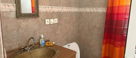 A bathroom with a sink, mirror, toilet, and a shower curtain.