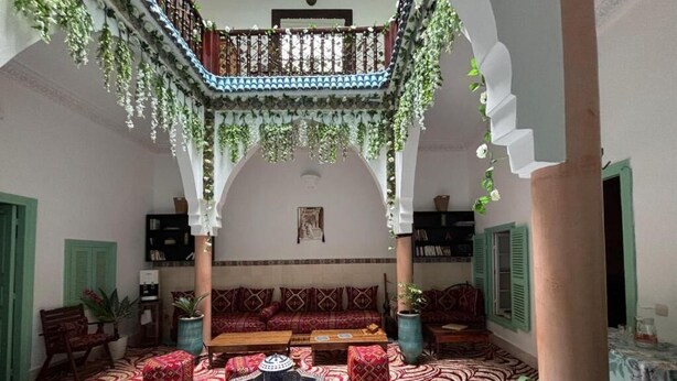 A traditional interior with a central seating area, a decorative fountain, and a balcony with hanging plants. - Riad Zahrat Al Fajr (El Jadida)