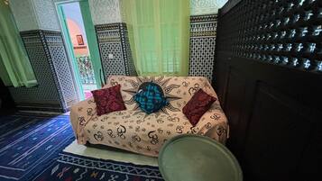 Una habitación tradicional con un sofá estampado, un cuenco decorativo y diseños intrincados en las paredes.