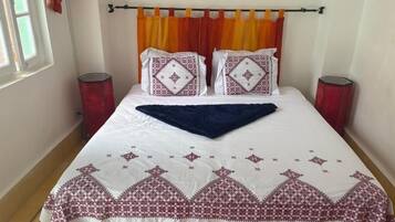 A bed with a white and red patterned bedspread, two matching pillows, and a blue throw blanket.